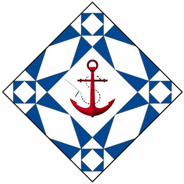 A red anchor is centered on a diamond-shaped quilt pattern with geometric blue and white triangles and squares—a nautical theme perfect for a quilt show in Tuckahoe NJ.