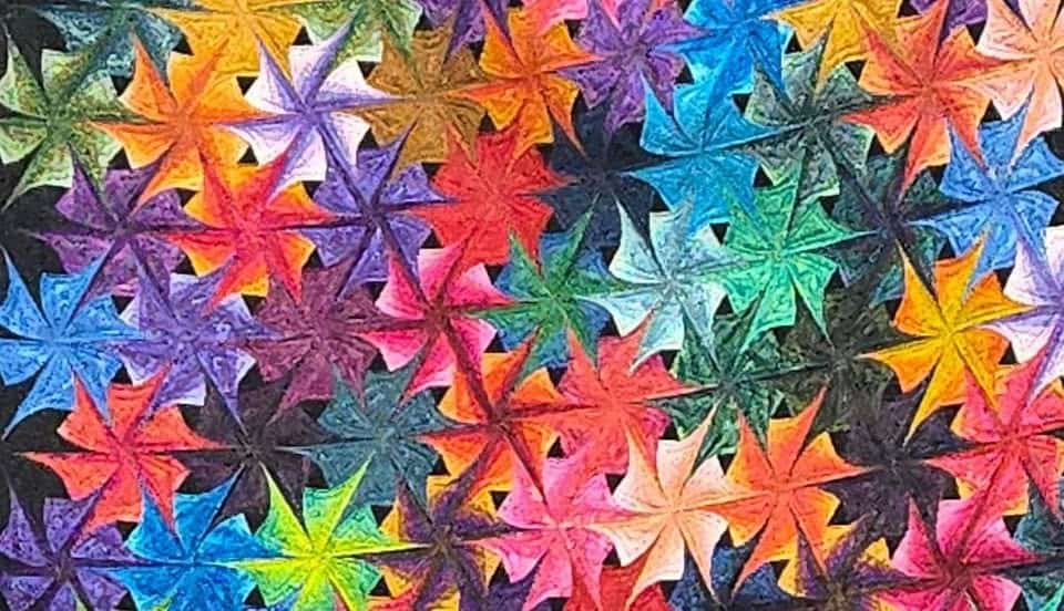 Ottawa-Quilt-Guild A vibrant pattern of overlapping, multicolored star shapes with pointed tips, arranged closely together to form an abstract, kaleidoscopic design—reminiscent of quilts showcased at the Quilt Show in Ottawa KS—against a dark background.