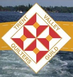 Trent-Valley-Quilters-Guild Diamond-shaped logo with a red and white quilt pattern in the center, surrounded by the words TRENT VALLEY QUILTERS GUILD on a yellow banner, set against a water and tree background.