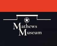 Logo for Mathews Museum featuring a star above the name, with Mathews and Museum written in large white letters on a black background and a red section at the top—perfect for promoting community events like the Quilt Show in Mathews Virginia.